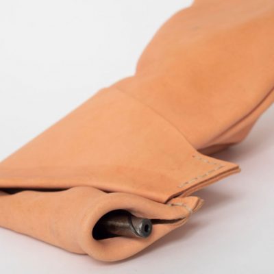 Folded and layered tan leather forming a rectangle shape with a cylindrical motorcycle part sticking out at one edge
