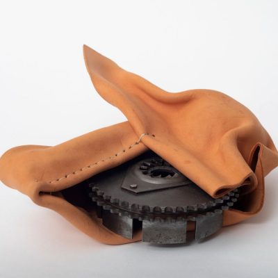 Molded tan leather in an abstract shape encasing a circular motorcycle part