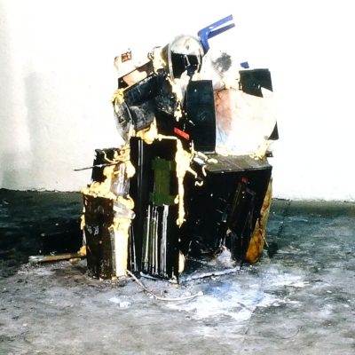 An abstract sculpture created from assorted discarded items piled and held together with spray foam