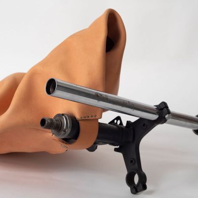 Molded and stitched tan leather with tubular motorcycle parts extending from the leather and holding one side of the work up off the ground